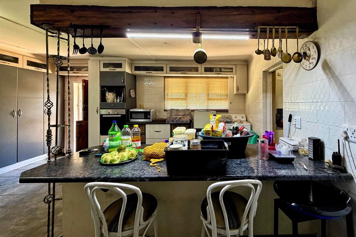 A functional kitchen featuring a central island, built-in cabinetry, and a rustic exposed timber beam overhead.