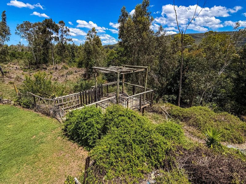 An elevated wooden viewing deck or gazebo structure situated within a natural farm landscape, showing significant signs of weathering and wear.