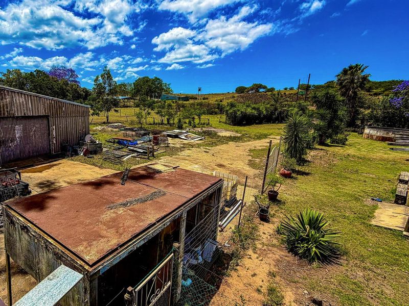 Expansive farm grounds featuring multiple outbuildings, corrugated metal structures, and open land with established trees and rural landscape views.