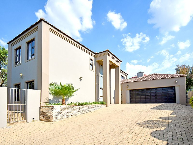 Front elevation of a modern double-story house featuring a paved driveway, double garage, and stone-clad garden bed.