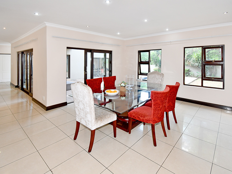 Spacious dining area featuring large format floor tiles, recessed lighting, and sliding glass doors providing seamless access to the outdoor patio.