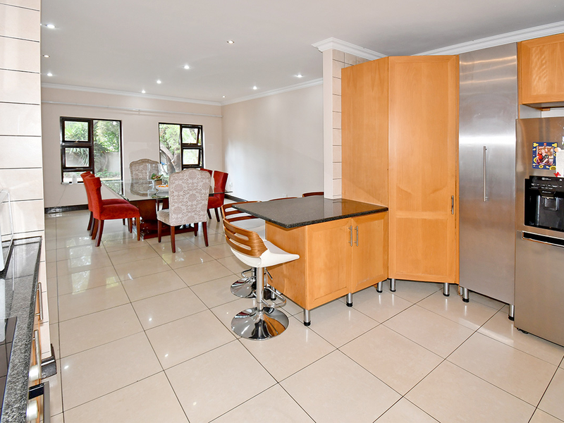 Spacious open-plan kitchen and dining area featuring tiled floors, granite countertops, built-in wooden cabinetry, and recessed lighting.