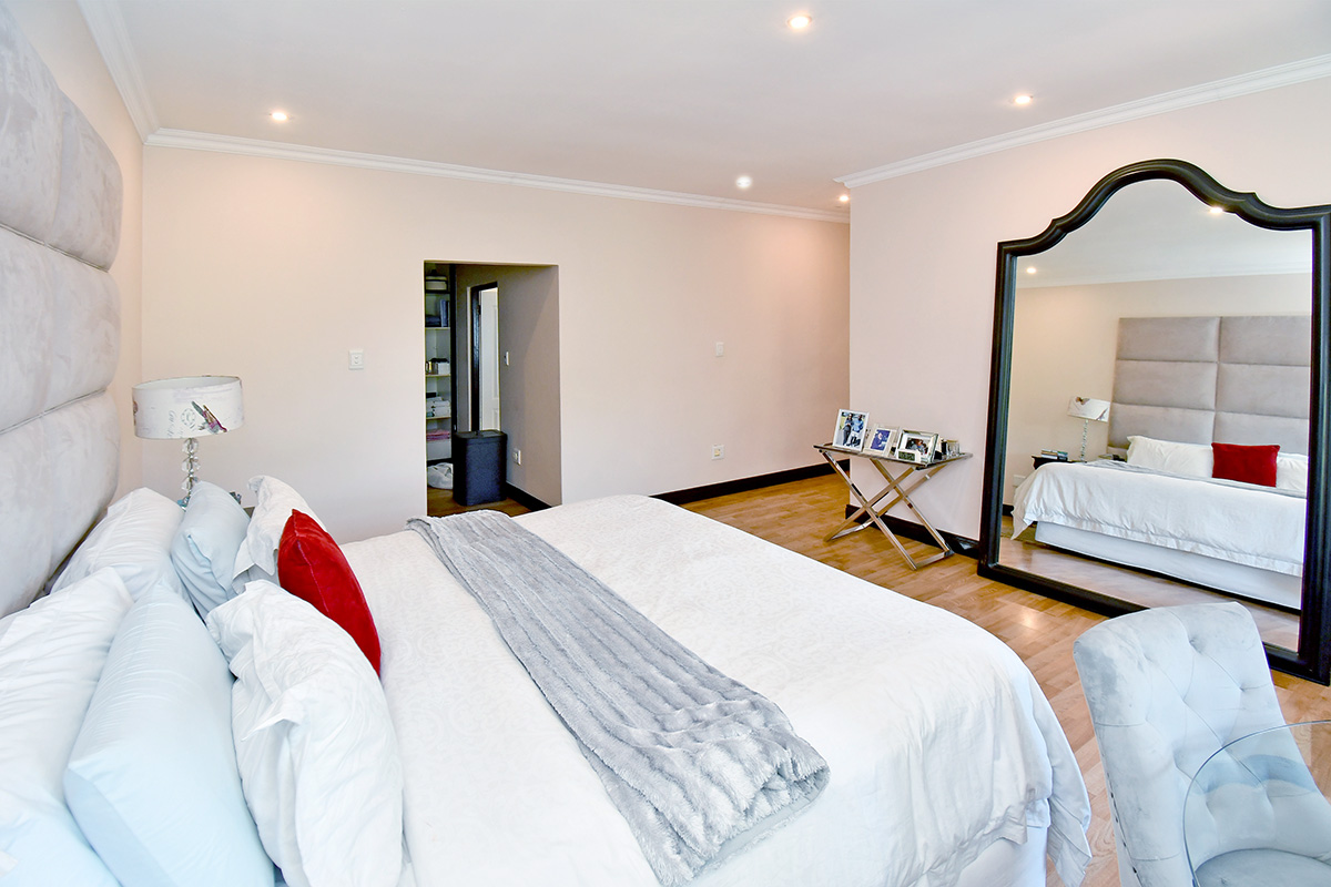 Spacious bedroom featuring laminate flooring, recessed downlighting, and a convenient walk-in closet area.