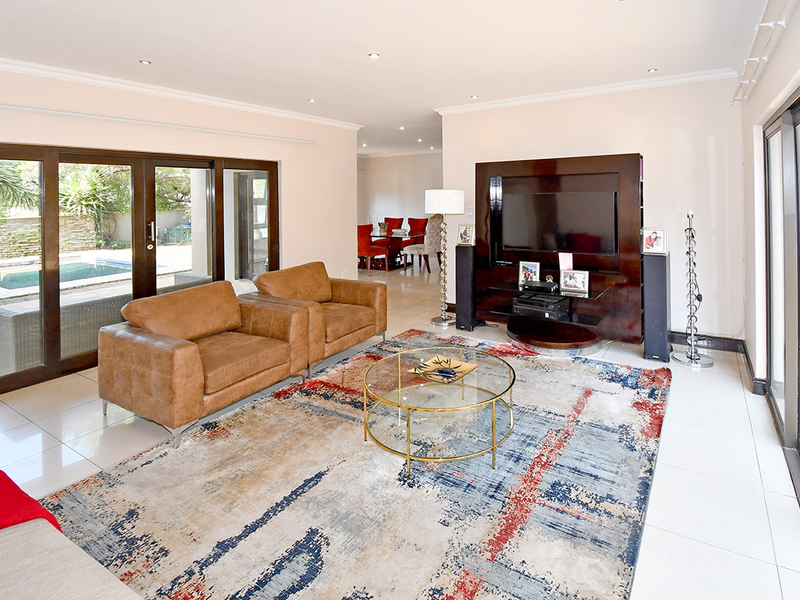 Spacious living room featuring tiled flooring, recessed lighting, and large sliding glass doors providing seamless access to the outdoor pool area.