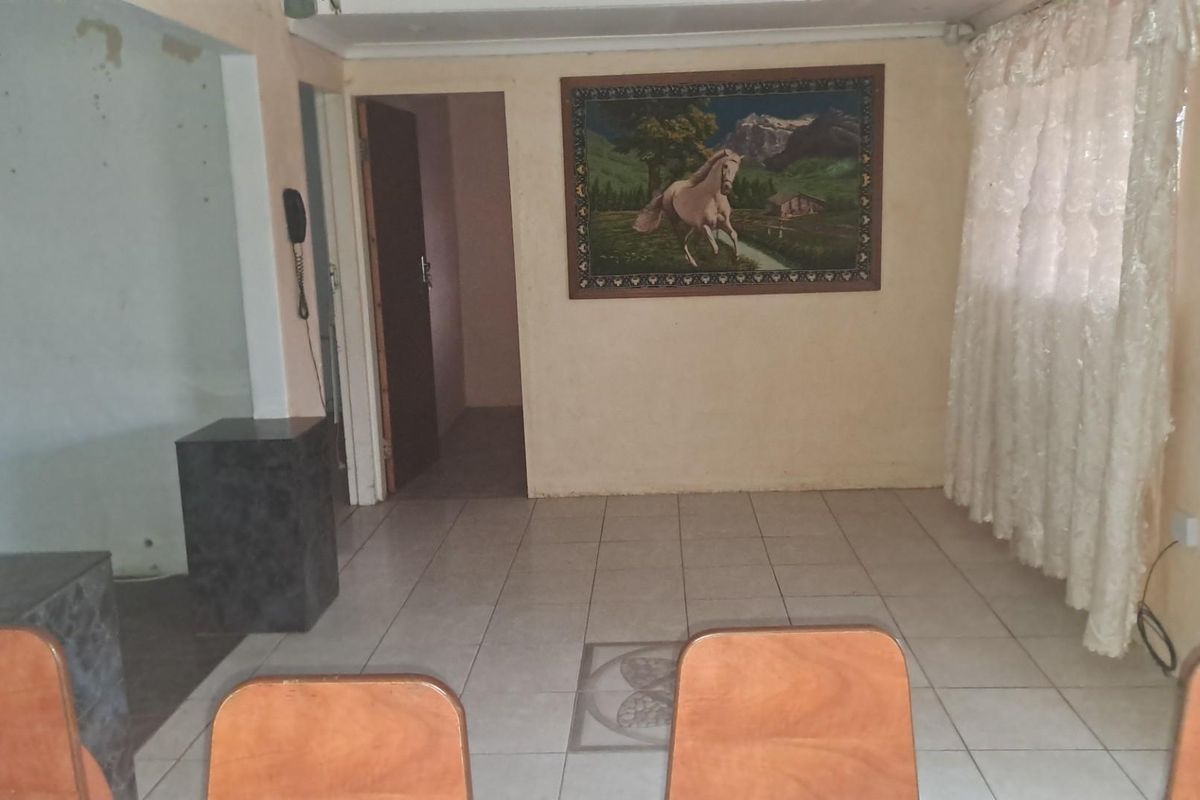 A living area featuring tiled flooring, neutral wall tones, and a doorway leading to an adjacent space.