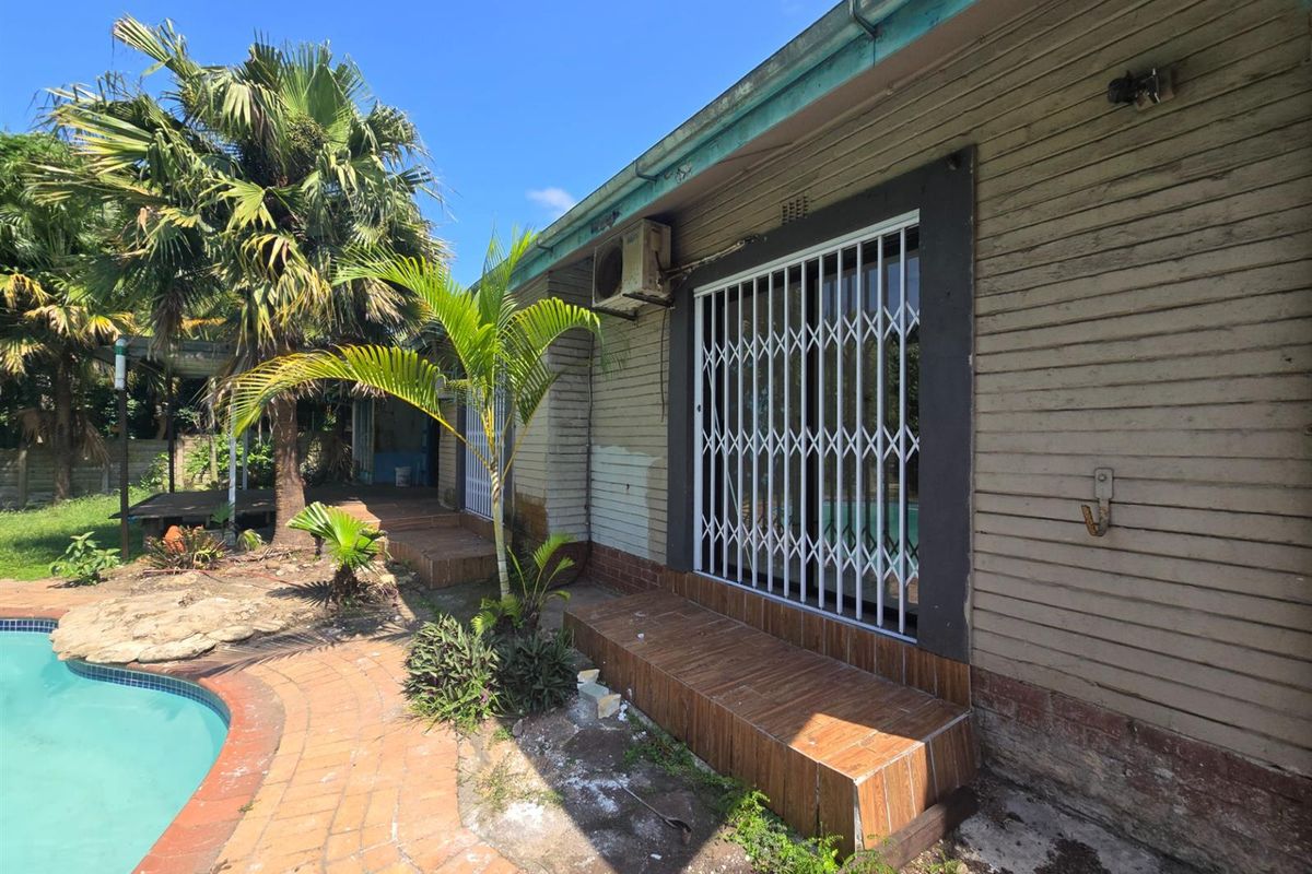 Rear exterior view of the property featuring a swimming pool, tiled step access, and security gate, showing signs of wear and maintenance requirements.