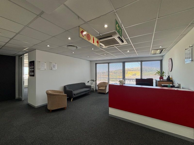 Professional office reception area featuring a built-in desk, suspended ceiling with integrated air conditioning, and large windows providing natural light and scenic views.