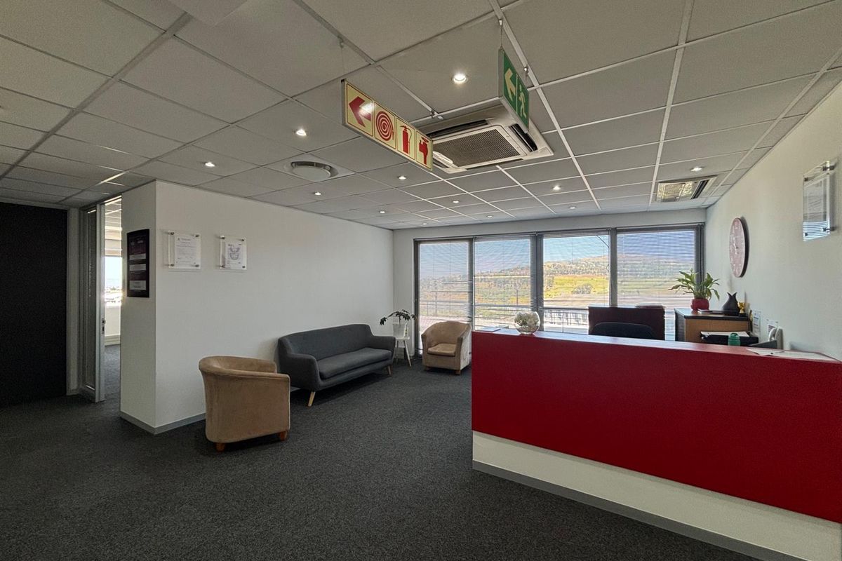 Professional office reception area featuring a built-in desk, suspended ceiling with integrated air conditioning, and large windows providing natural light and scenic views.