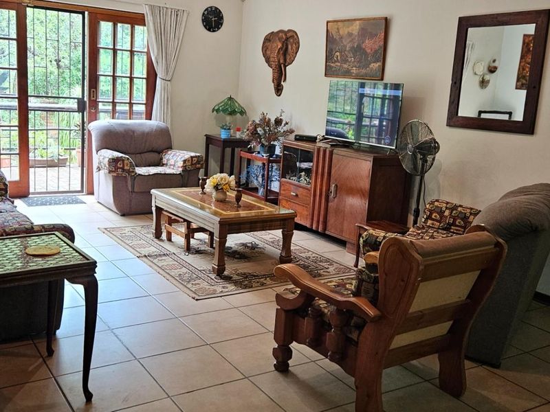 A spacious living room featuring tiled flooring and a large sliding glass door that provides access to the outdoor area.