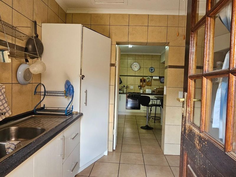 A functional scullery area featuring a double stainless steel sink, tiled splashbacks, and built-in cabinetry, providing a practical secondary workspace adjacent to the main kitchen.