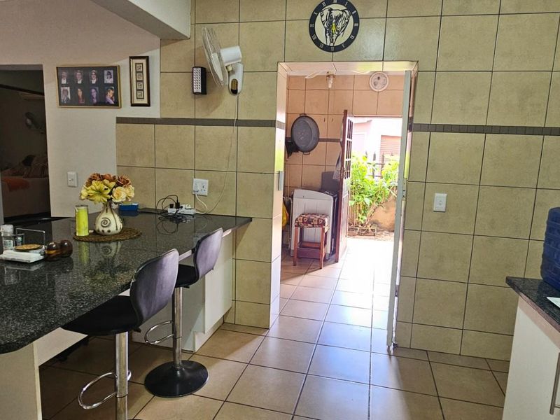 Kitchen area featuring granite countertops, a breakfast bar, and tiled finishes, with an open doorway leading to an exterior space.