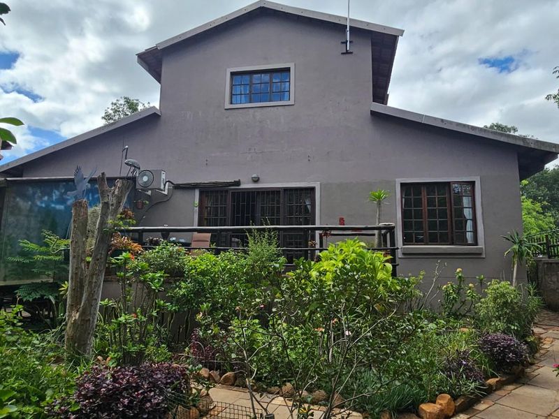 Rear view of the house featuring a timber deck, established garden, and exterior wall finishes with a solar geyser installed on the roof.