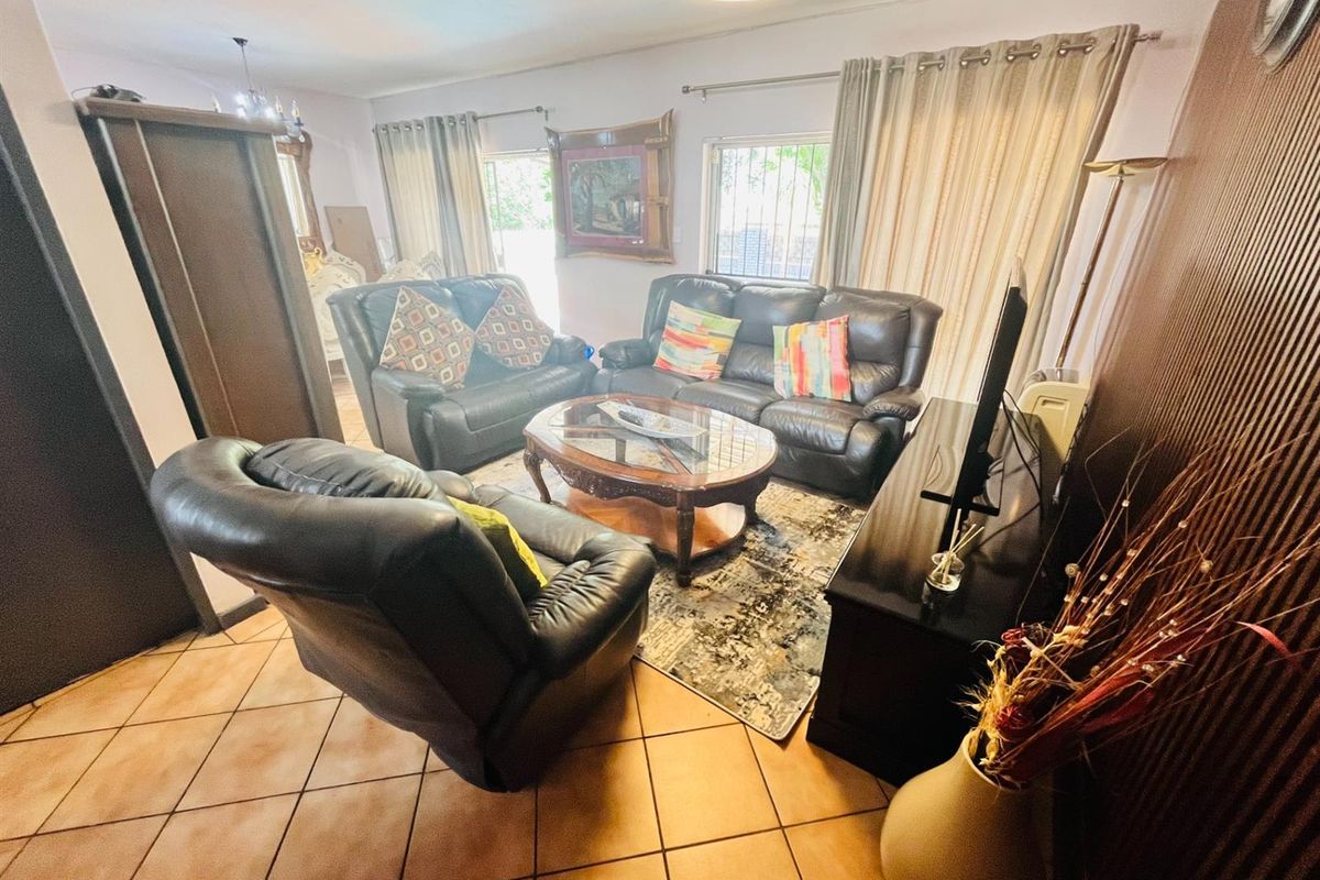 A living room featuring tiled flooring, natural light from a sliding door, and neutral wall finishes.