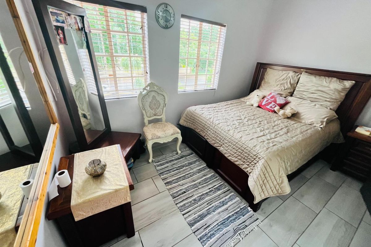 A bedroom featuring tiled flooring, crown molding, and dual windows with venetian blinds, providing a functional and well-lit sleeping space.