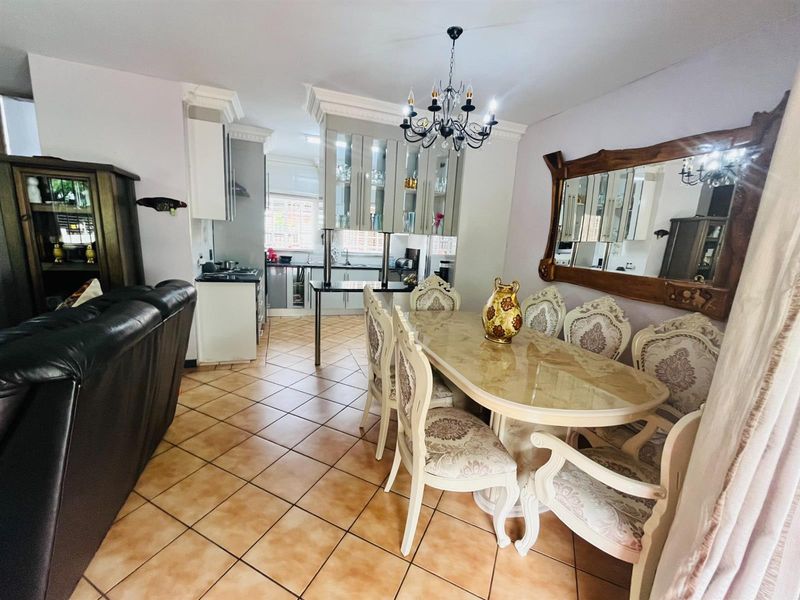Open-plan living and dining area featuring ceramic floor tiles, crown molding, and a functional kitchen with built-in cabinetry and a breakfast island.