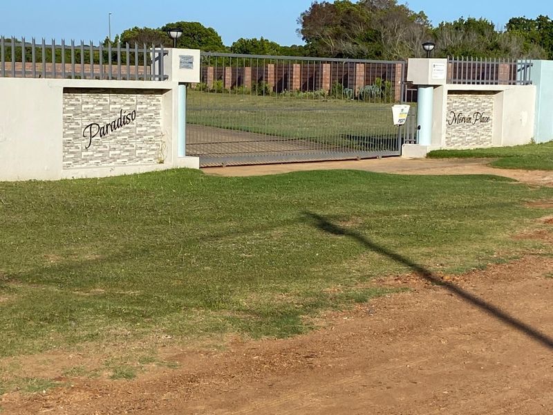 Front entrance view of the property featuring a secure metal gate, masonry boundary walls with stone cladding, and integrated pillar lighting.