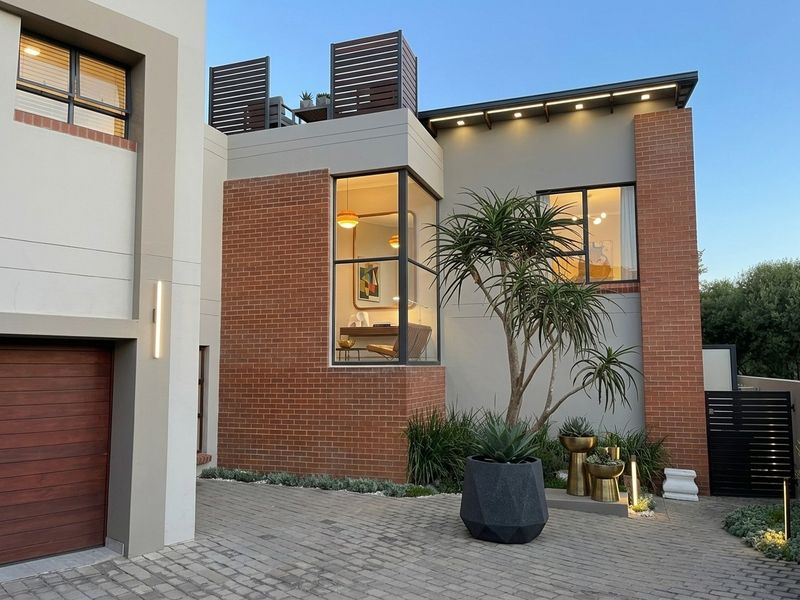 Modern architectural front facade featuring a combination of brick and smooth render, a paved driveway, and a prominent corner window design.