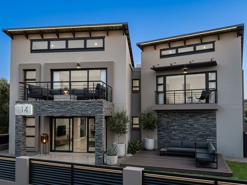 Modern double-storey residence featuring contemporary architectural design, stacked stone accents, timber decking, and private balconies with integrated lighting.