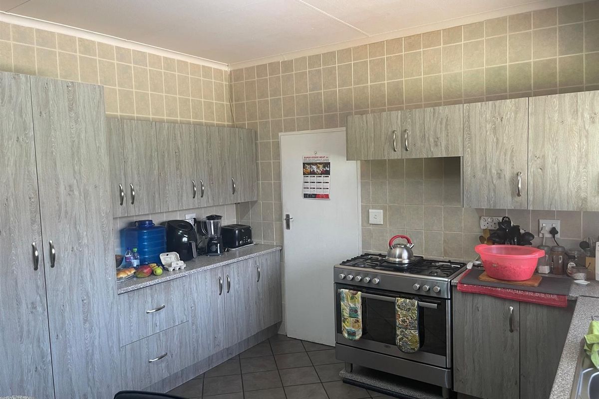 A functional kitchen featuring wood-look cabinetry, tiled splashbacks, and a freestanding gas stove with oven.