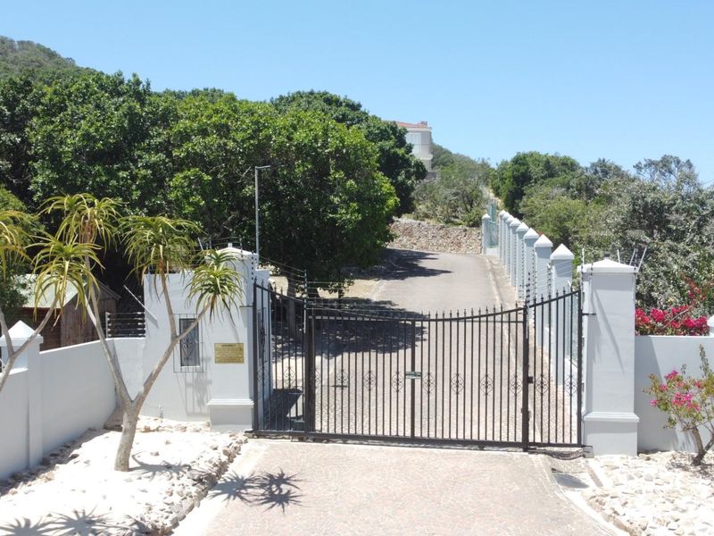 A secure gated entrance to the Royal Alfred Estate, featuring a paved driveway, perimeter walling, and established landscaping.