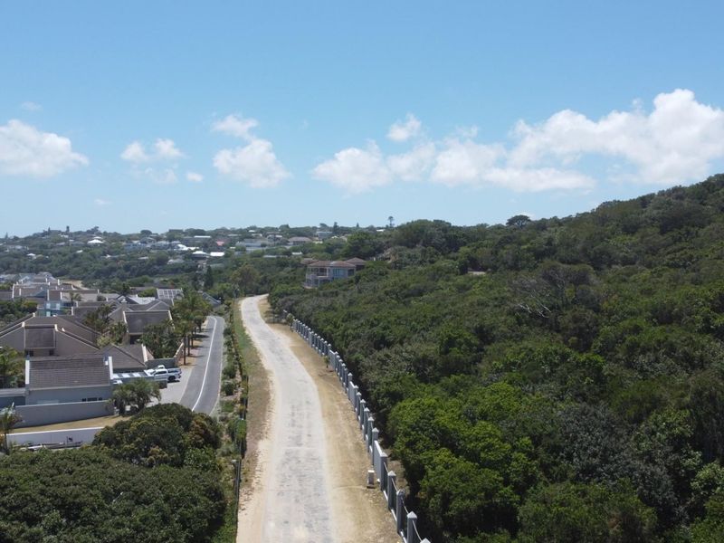 An aerial view of the residential land, showcasing the surrounding neighborhood, access road, and established coastal vegetation.