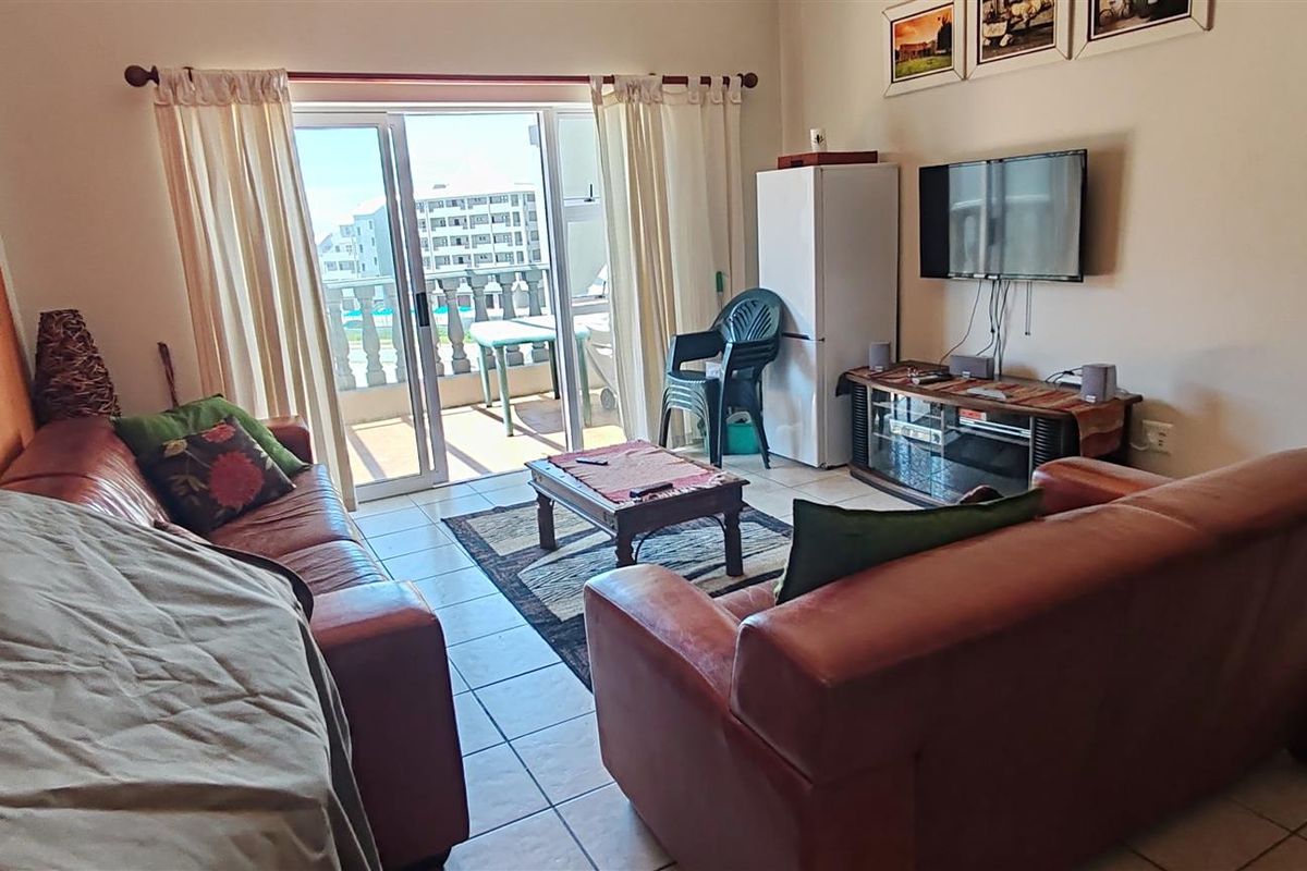 A comfortable living room featuring tiled flooring and large sliding glass doors that provide access to an outdoor balcony area.