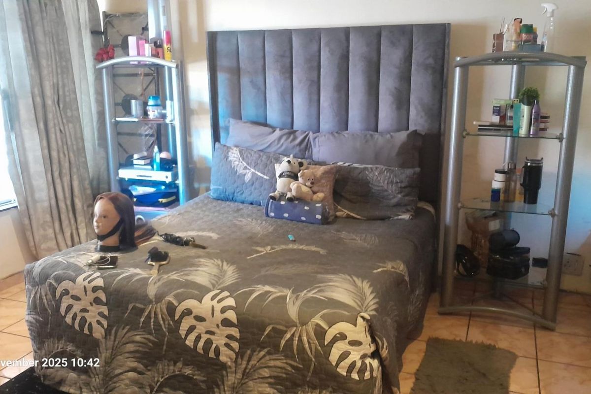 A bedroom featuring tiled flooring and a large upholstered headboard, providing a functional space for rest.