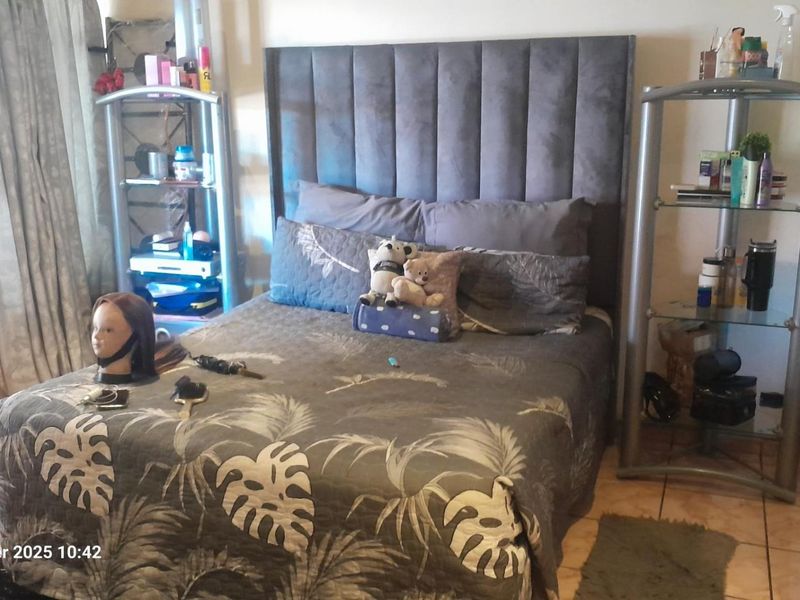 A bedroom featuring tiled flooring and a large upholstered headboard, providing a functional space for rest.