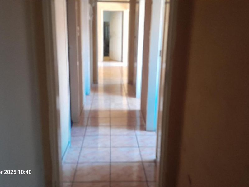 A simple, tiled hallway connecting multiple rooms within the property.