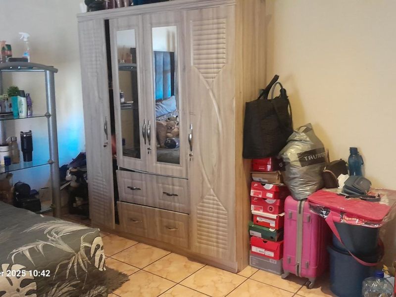 A bedroom featuring tiled flooring and a built-in wardrobe unit.