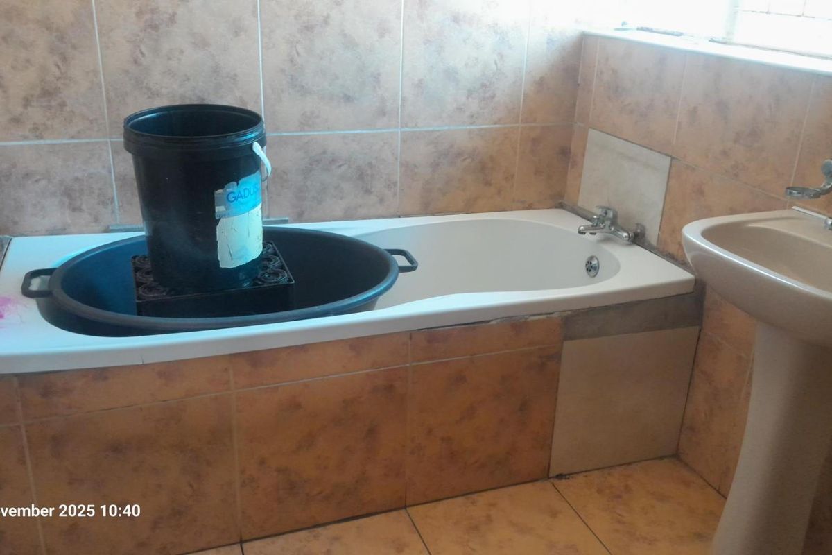 A bathroom featuring a bathtub and pedestal basin with tiled finishes, currently requiring completion of tiling and minor repairs to the bathtub surround.