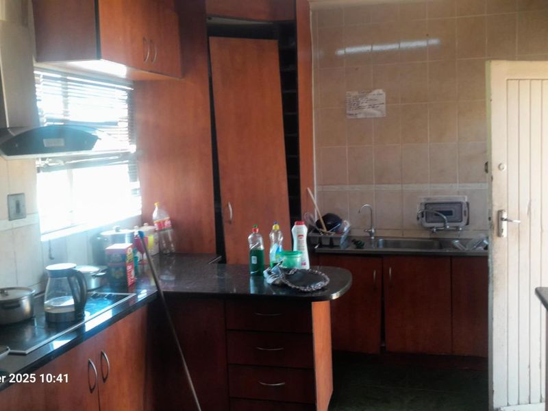 A dated kitchen featuring wood-finish cabinetry, granite countertops, and a tiled backsplash, requiring minor repairs to cabinetry and cosmetic updates.