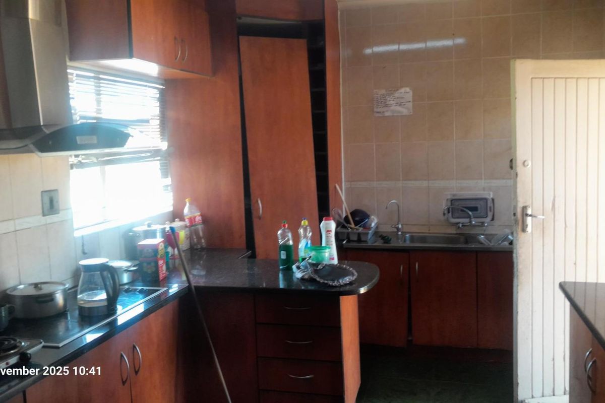 A dated kitchen featuring wood-finish cabinetry, granite countertops, and a tiled backsplash, requiring minor repairs to cabinetry and cosmetic updates.