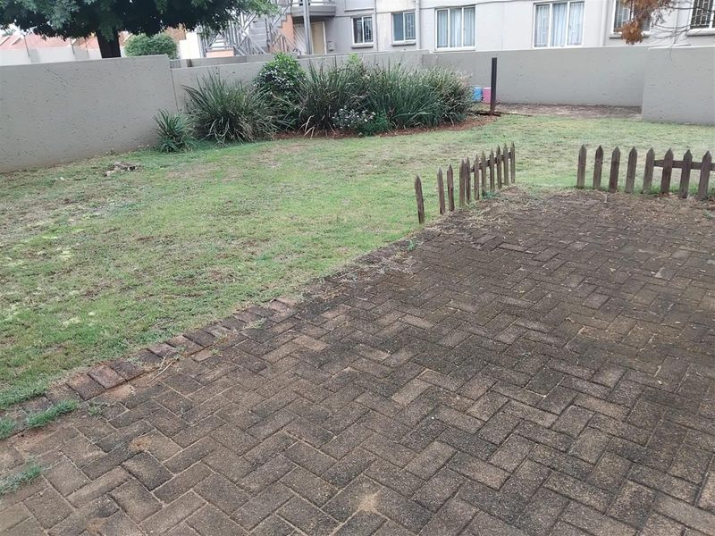 A private rear garden featuring a paved patio area, a small lawn, and a perimeter boundary wall.