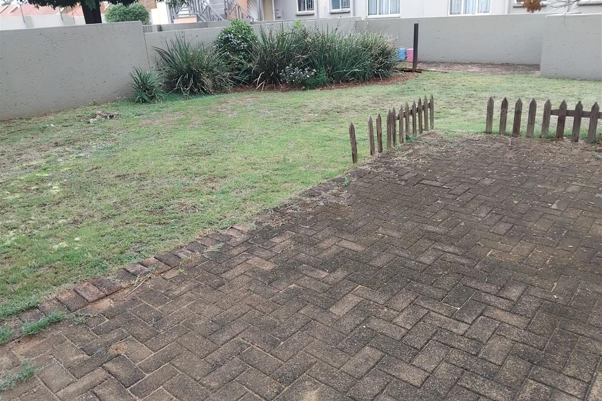 A private rear garden featuring a paved patio area, a small lawn, and a perimeter boundary wall.