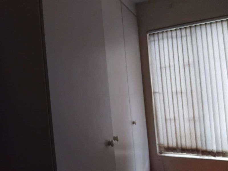 A bedroom featuring built-in cupboards and vertical window blinds.