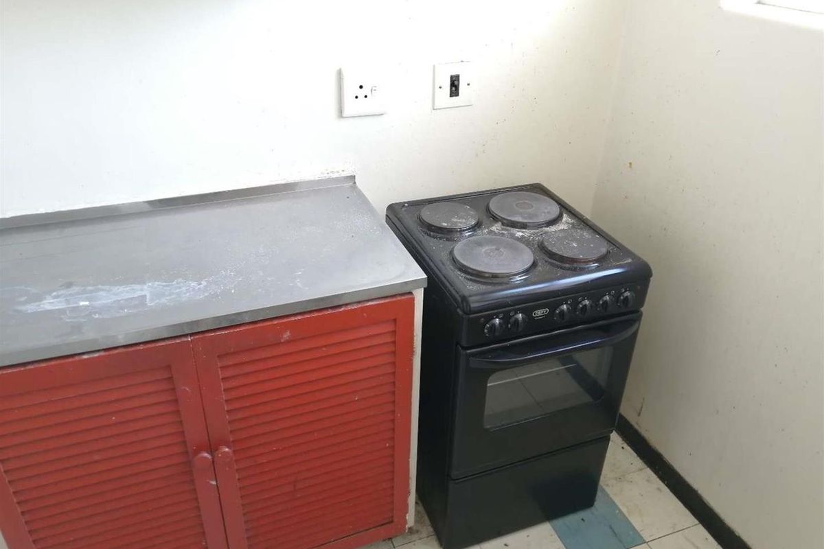 A basic kitchen area featuring a stainless steel countertop, red cabinetry, and a freestanding electric stove.