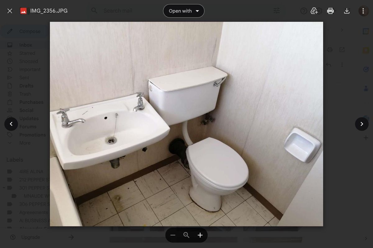 A compact bathroom featuring a wall-mounted basin and a standard toilet, requiring significant cosmetic updates and modernization of finishes.