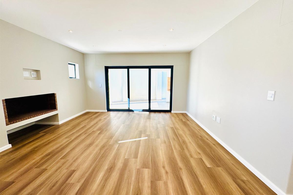 Spacious, light-filled living room featuring modern laminate flooring, a built-in fireplace, and large sliding glass doors leading to the exterior.
