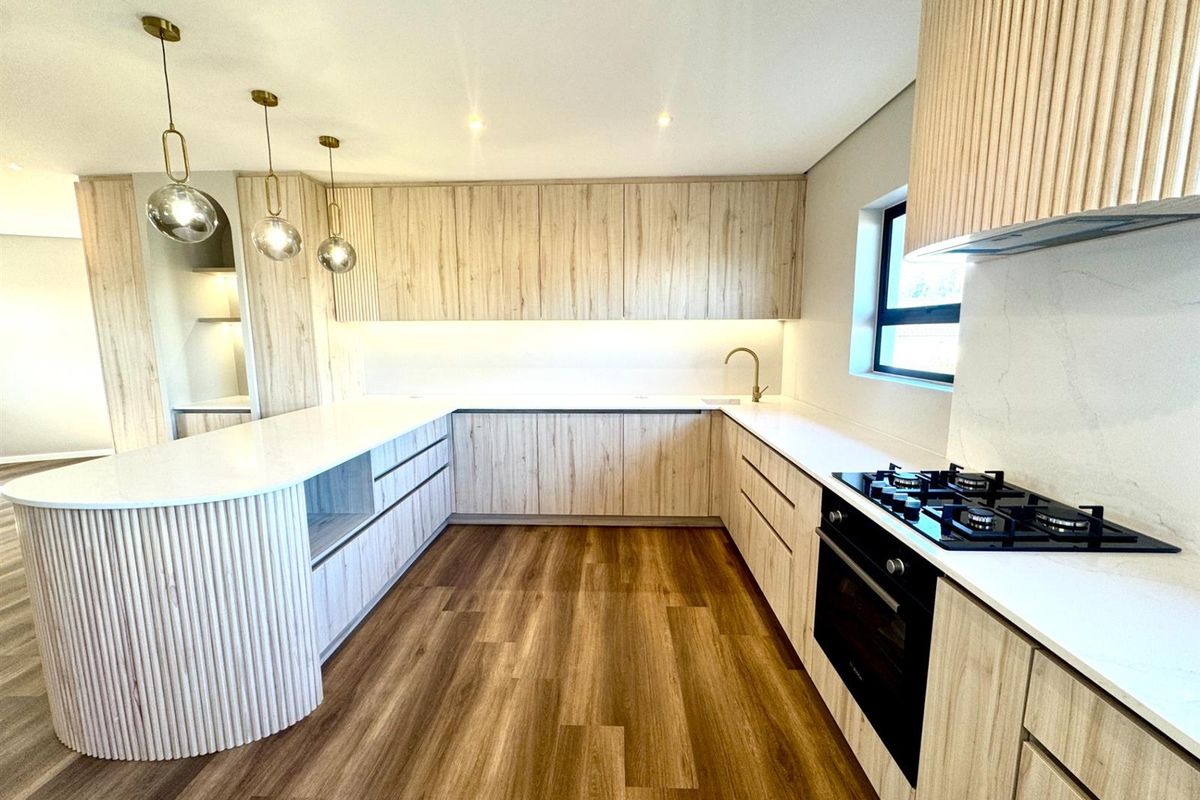 Modern kitchen featuring light wood cabinetry, stone countertops, integrated gas hob, built-in oven, and high-quality finishes throughout.