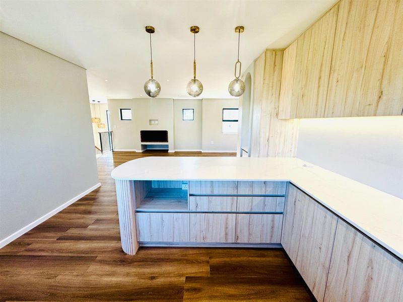 Modern open-plan living area featuring a contemporary kitchen with stone countertops, light wood cabinetry, and a seamless transition to the spacious living room.