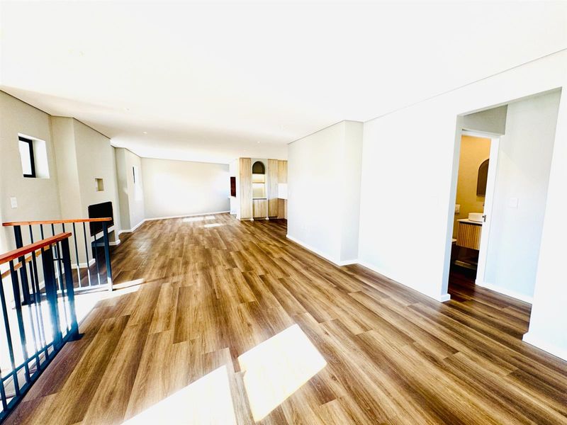Spacious open-plan living area featuring modern laminate flooring, a built-in fireplace, and neutral finishes, offering a bright and versatile layout.