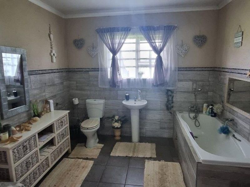 A functional bathroom featuring a pedestal basin, toilet, and built-in bathtub with tiled wall cladding and flooring.