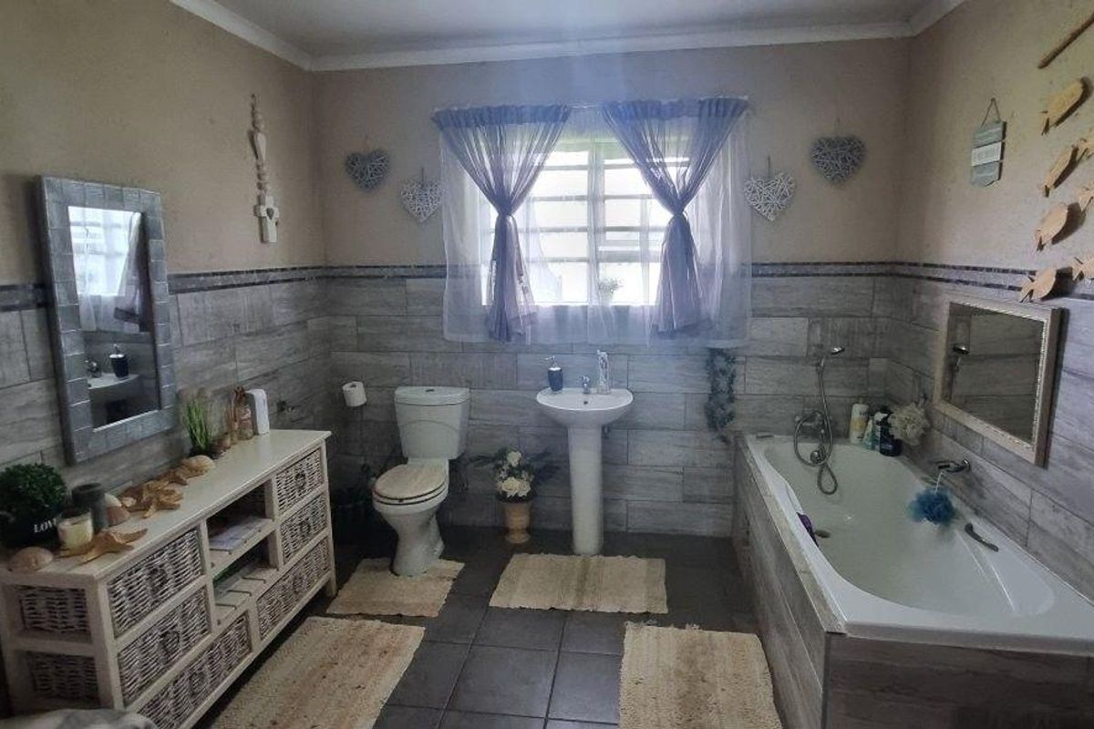 A functional bathroom featuring a pedestal basin, toilet, and built-in bathtub with tiled wall cladding and flooring.