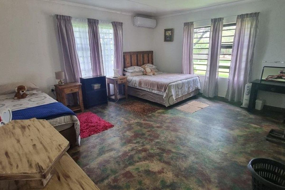 Spacious bedroom featuring large windows for natural light, a wall-mounted air conditioning unit, and unique concrete flooring.