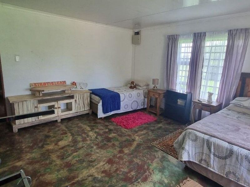 Spacious bedroom featuring polished concrete flooring, an integrated air conditioning unit, and large windows with security bars.