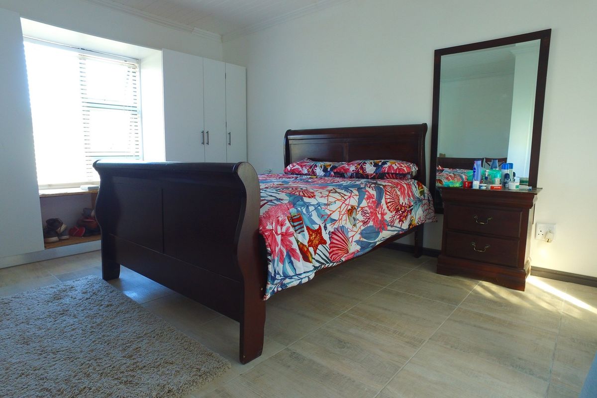 A bedroom featuring built-in white cabinetry, tiled flooring, and a window with natural light.