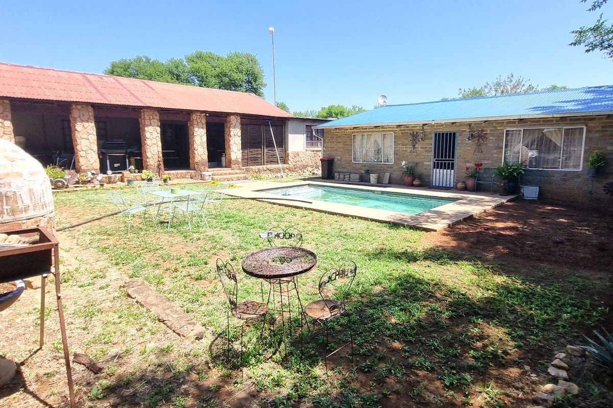 Rear garden area featuring a swimming pool, stone-clad structures, a covered patio, and a built-in brick pizza oven.
