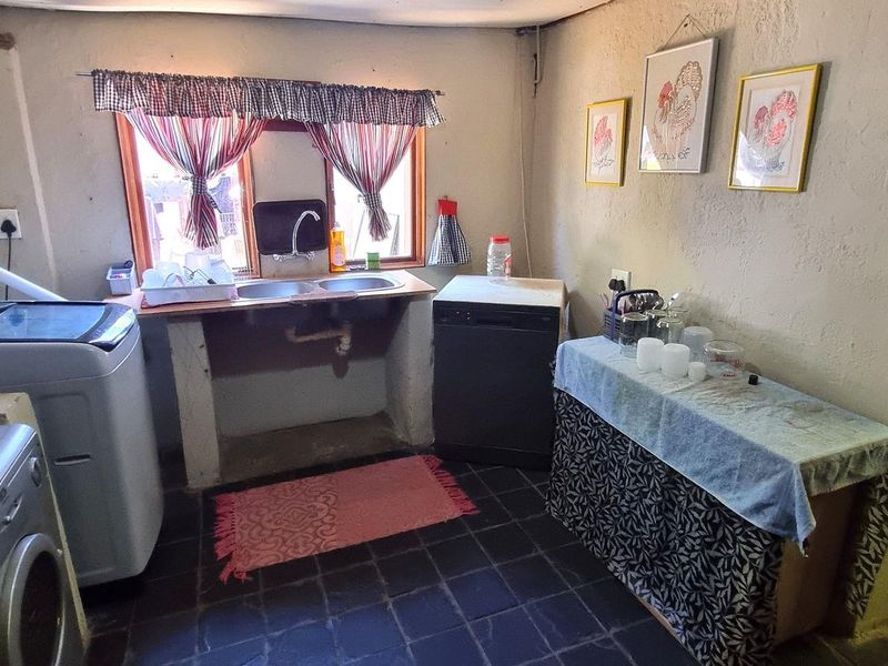A functional laundry area featuring a double basin sink, tiled flooring, and dedicated plumbing connections for washing appliances.