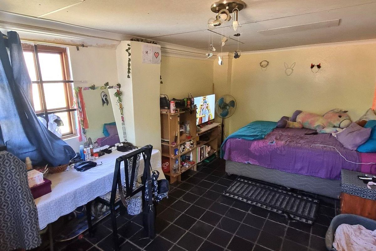 A bedroom featuring dark tiled flooring and a central ceiling light fixture, requiring some cosmetic updates to the walls and ceiling.